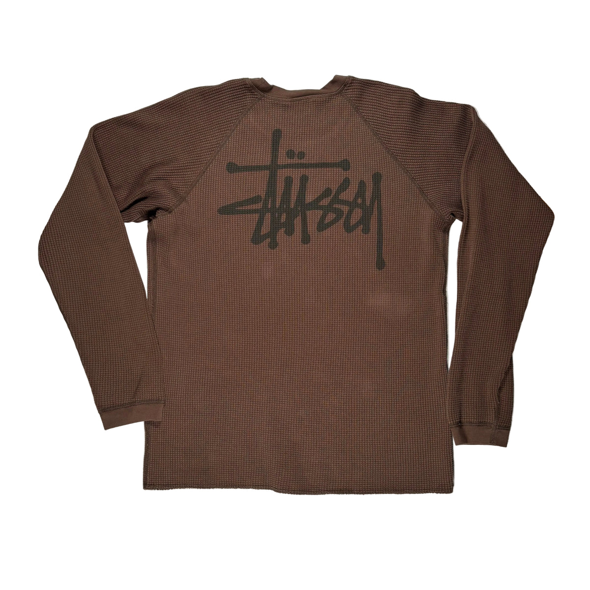 A brown ribbed long-sleeve shirt with a large black Stüssy logo printed across the back, laid flat on a white surface.