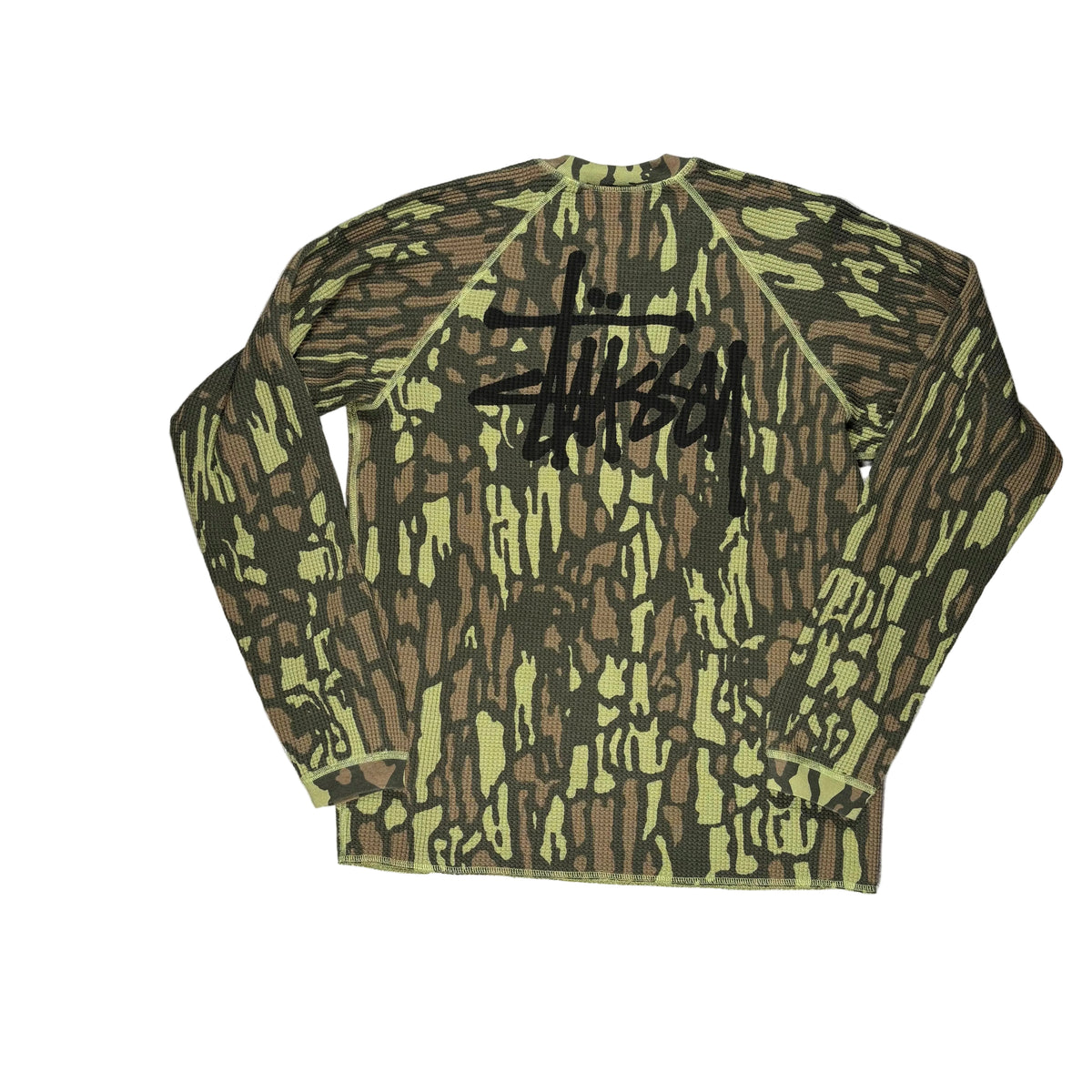 A Stussy camouflage long-sleeve shirt with a large black Stussy logo across the back, laid flat on a white sheet of paper.