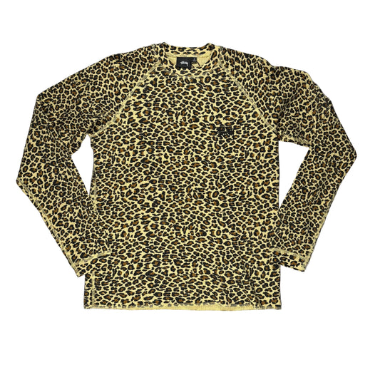 A long-sleeve crewneck shirt with a tan and black leopard print pattern, laid flat on a white surface.