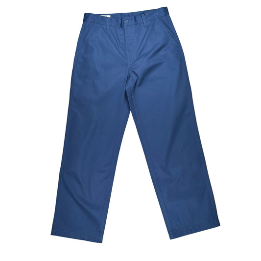 A pair of blue chino pants laid flat on a white surface.