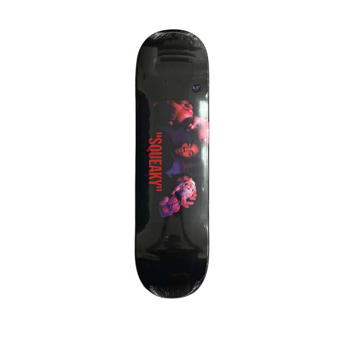 A skateboard deck in its shrink wrap, featuring a black background with a red 'SQUEAKY' text graphic and a purple-toned character illustration, displayed on a white surface.