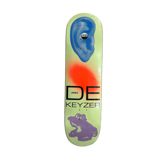 A skateboard deck featuring a lime green background with a blue ear graphic, a red spray-paint style oval, a purple frog graphic, and the text 'DE KEYZER'.