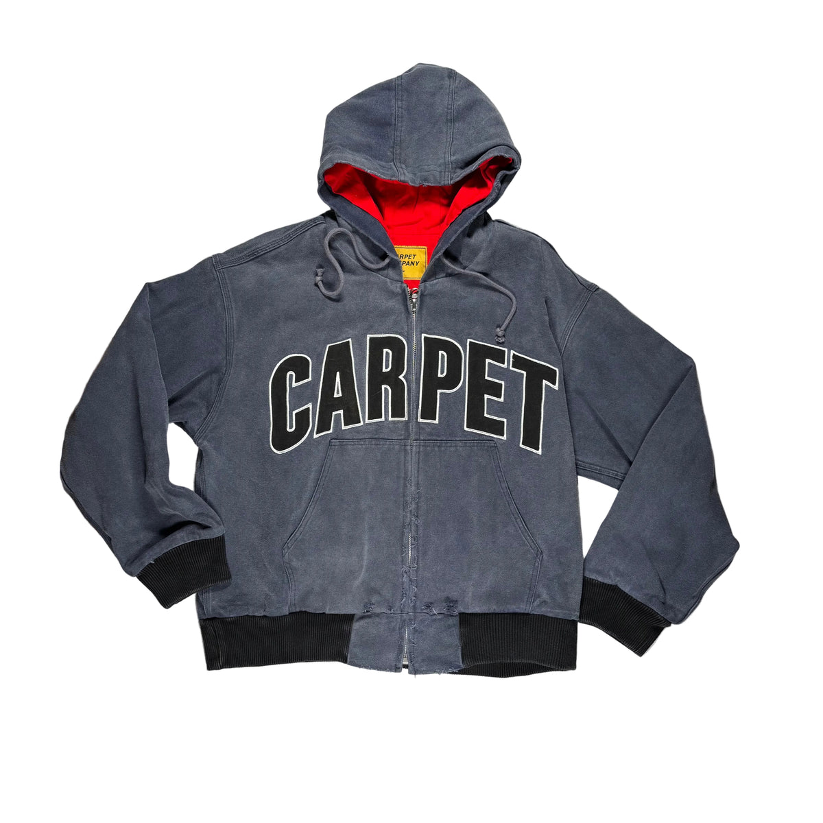 A charcoal gray zip-up hooded jacket with 'CARPET' printed across the chest in black varsity letters with a white outline. Featuring a red interior hood lining and black ribbed cuffs and hem, laid flat on a white.