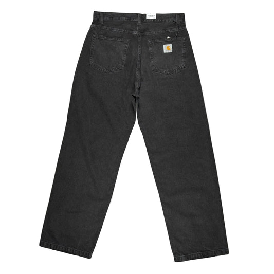 Black Carhartt denim jeans shown from the back, laid flat on a white surface. The Carhartt brand patch is visible on the back right pocket.