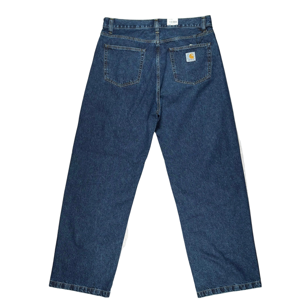 Back view of a pair of blue denim jeans laid flat on a white surface. The jeans show  a visible Carhartt logo patch on the right back pocket.