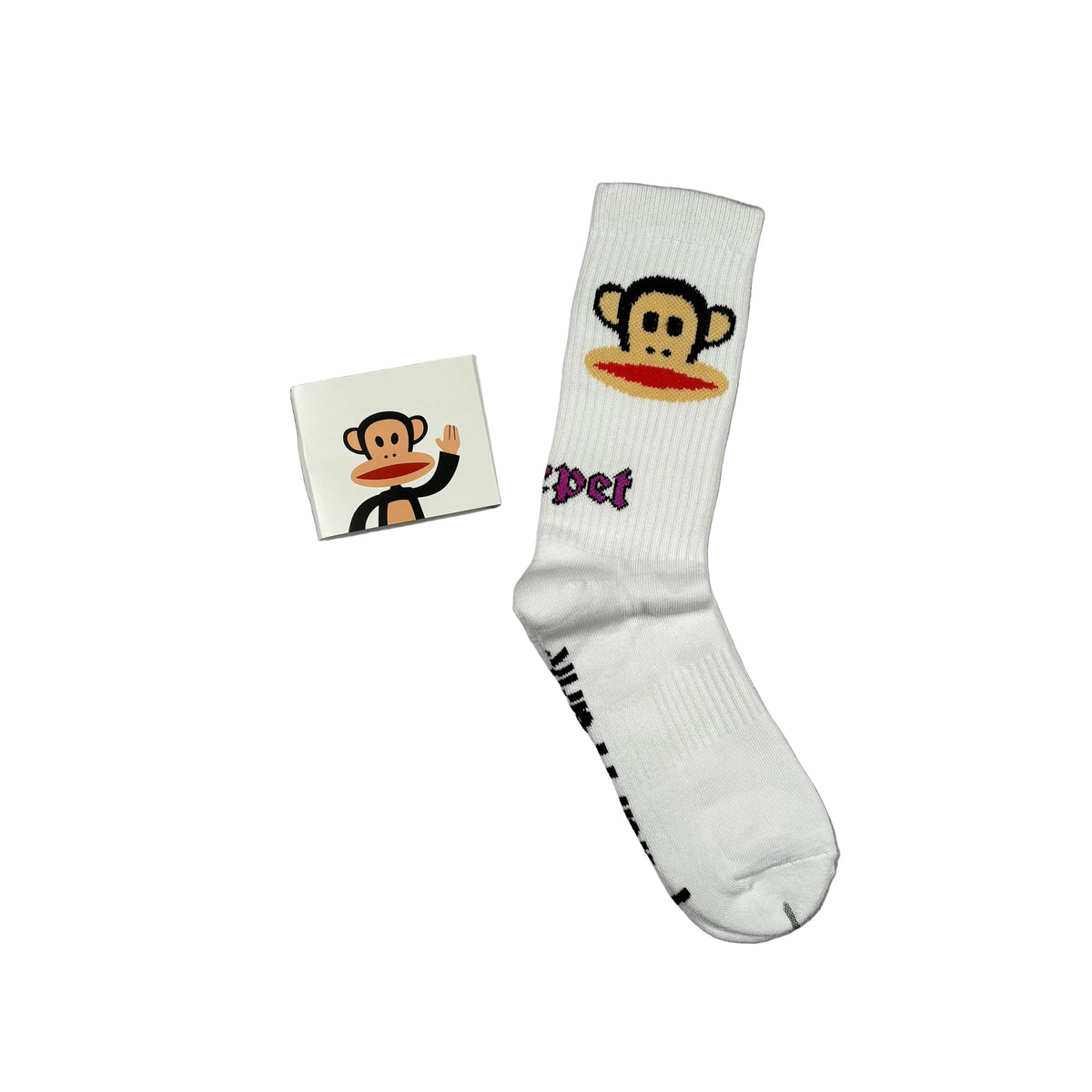 A white crew sock with a cartoon monkey face graphic and purple 'Carpet' text, shown next to a small matching square card on a white background.