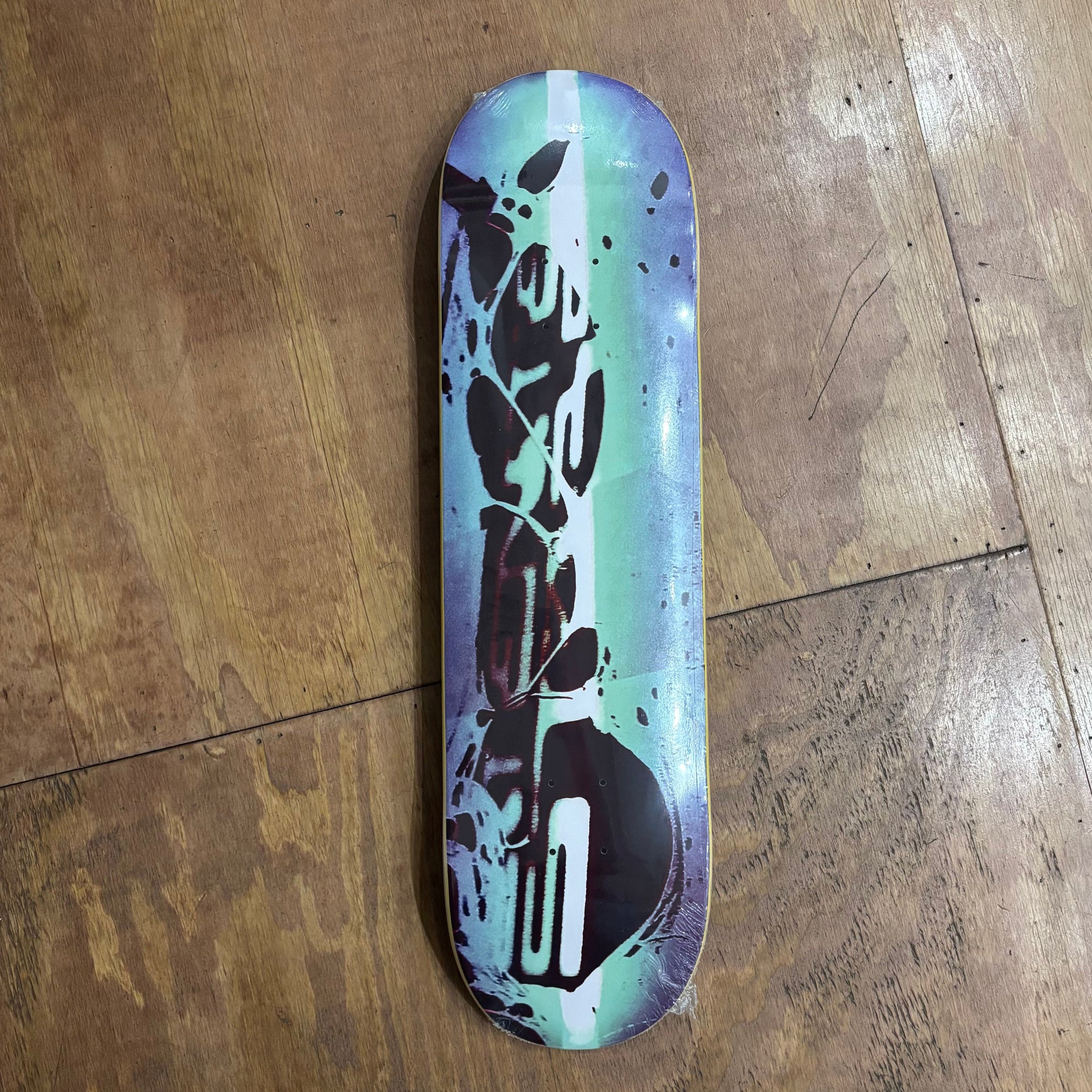 overview of blue, green and black abstract logo on skateboard deck