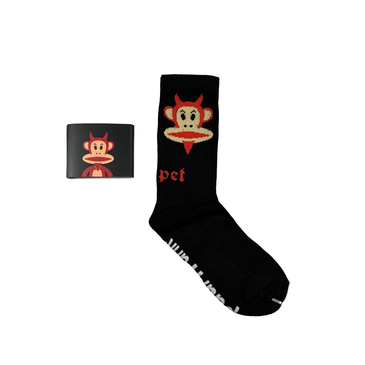 A black crew sock featuring a red, beige, and white cartoon monkey face graphic with the text 'Carpet' below it, displayed next to a small black square card with the same graphic on a white background.