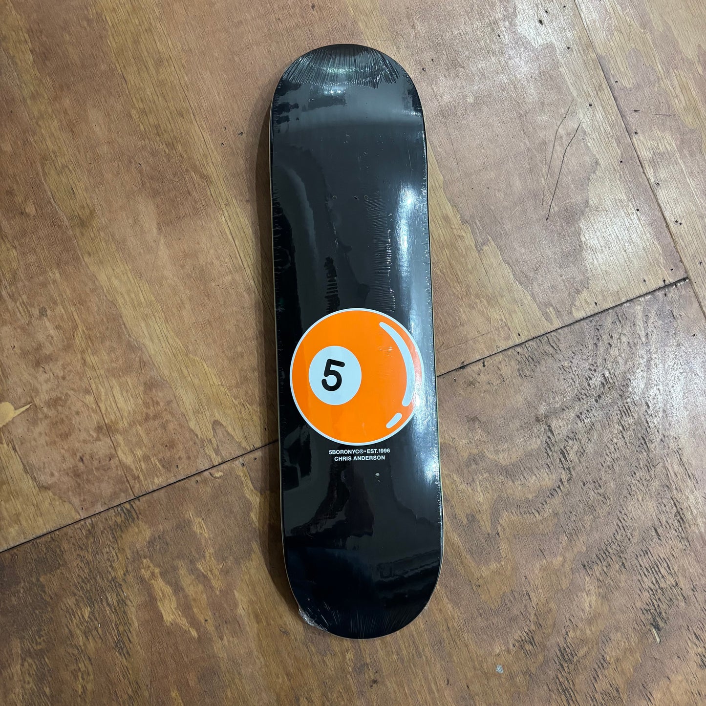 black skateboard deck with orange 5 ball on lower portion of deck
