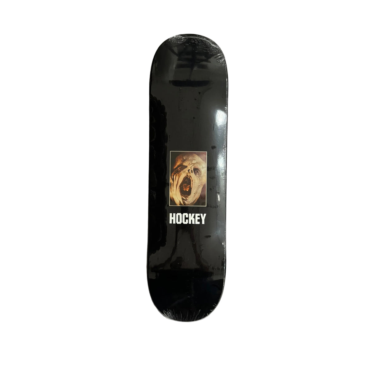A black skateboard deck with a graphic of a screaming face and the word 'HOCKEY' printed in white, wrapped in protective plastic on a white surface.