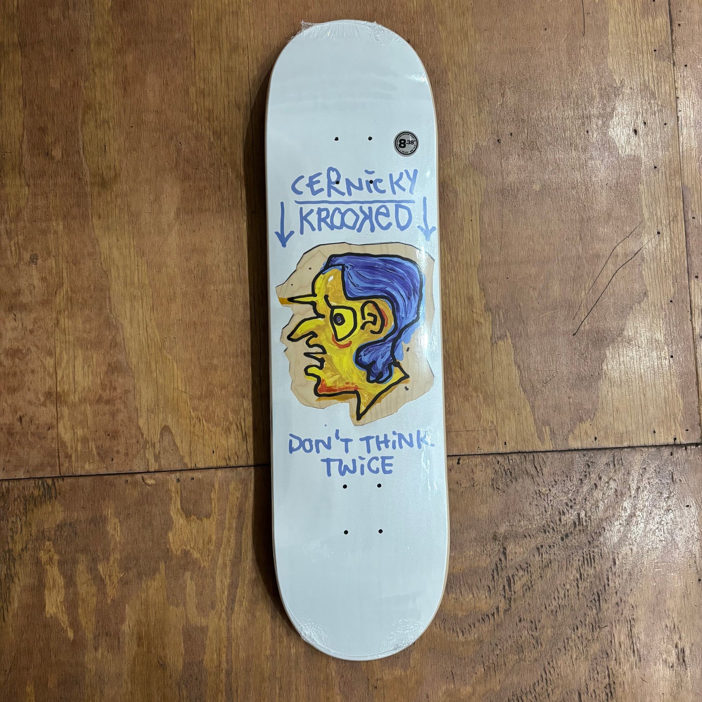 white skateboard deck with yellow and blue headfigure on center of deck, and CERNICKY KROOKED above the graphic, and DON'T THINK TWICE under the head