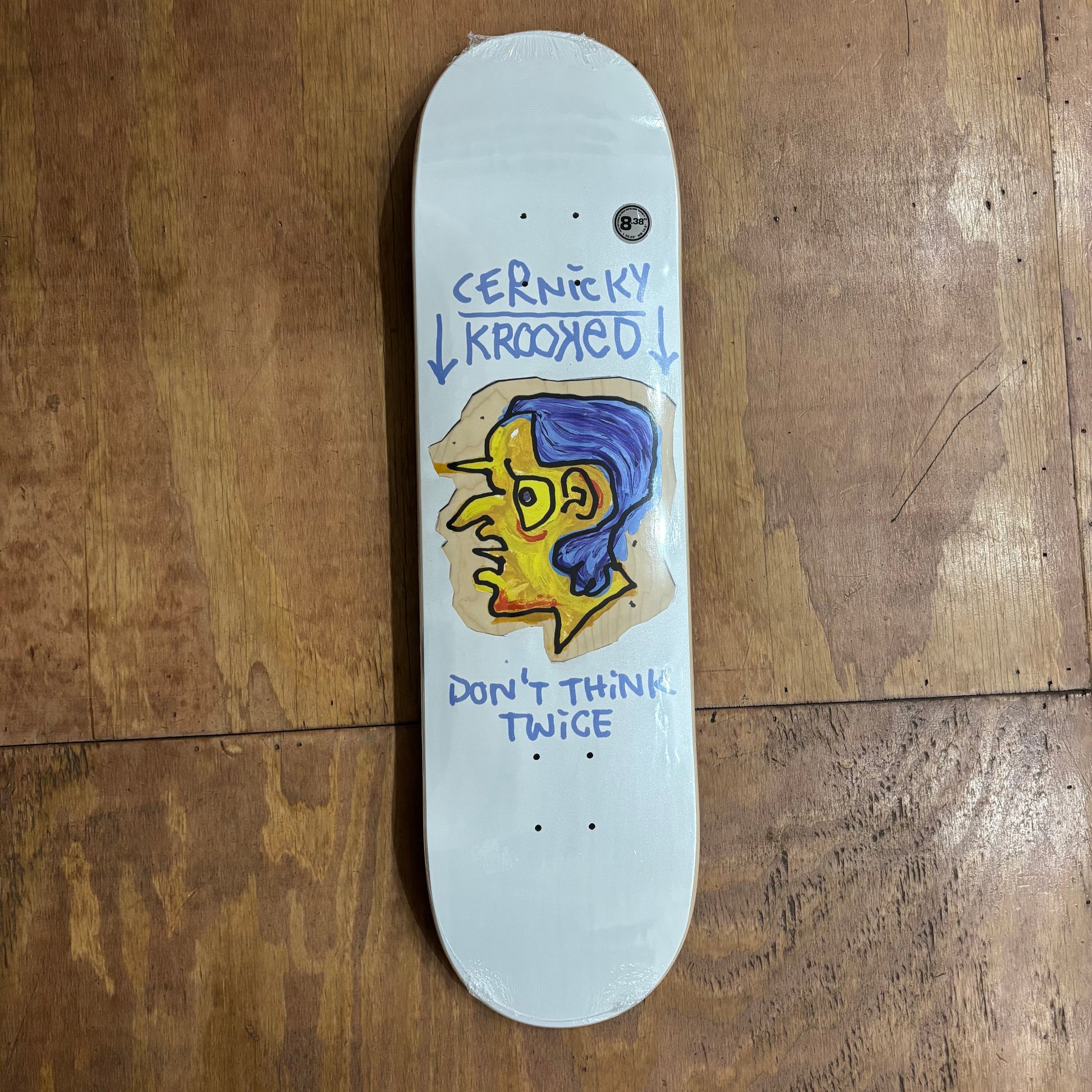 white skateboard deck with yellow and blue headfigure on center of deck, and CERNICKY KROOKED above the graphic, and DON'T THINK TWICE under the head