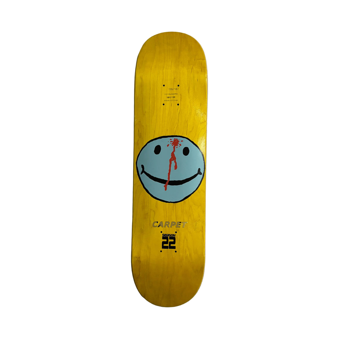 A yellow skateboard deck featuring a light blue smiley face graphic with a red blood drip detail, displayed vertically on white surface.