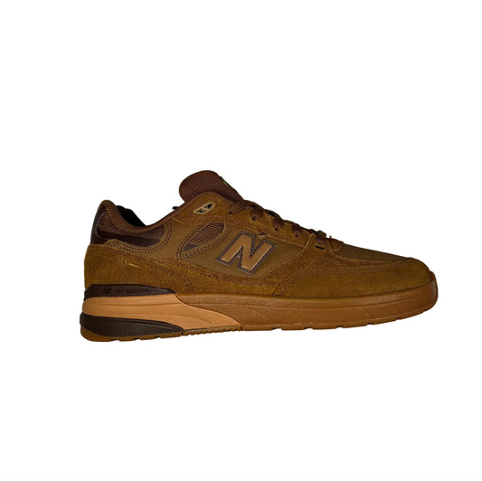 A single New Balance sneaker in brown suede and mesh, positioned horizontally on a white surface.