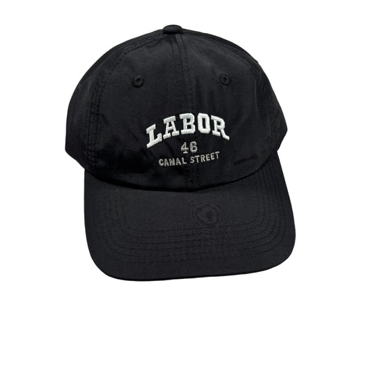 A black baseball cap with white embroidered text reading 'LABOR 48 CANAL STREET' on the front, photographed on a light white surface.