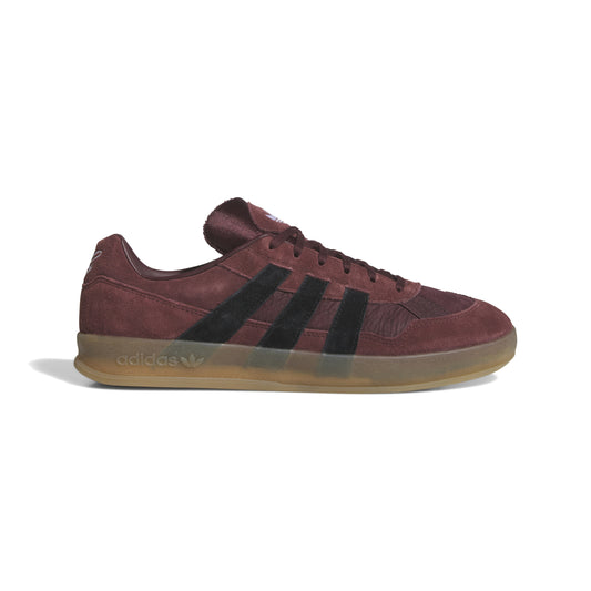 side view of maroon suede lowtop sneaker with gum sole and black stripes