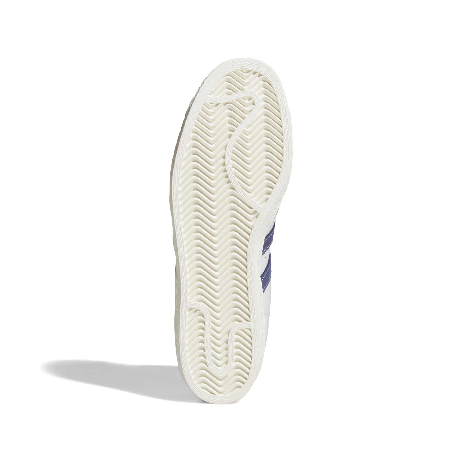 A close-up of a white sneaker's textured outsole, showing the tread pattern and a partial view of navy blue side stripes, on a white background.