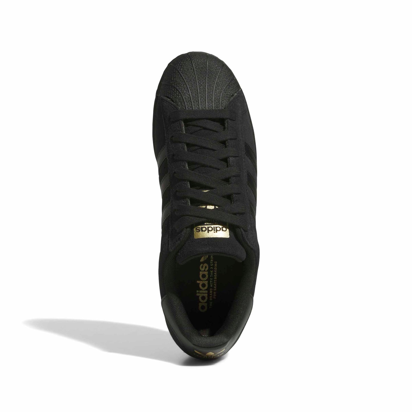 A single black Adidas Superstar sneaker shown from a top-down view on a white background, featuring a metallic gold logo on the tongue and gold branding on the inner sole.